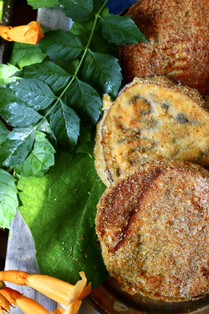 golden crispy breaded eggplant cutlets with green leaves and orange flowers