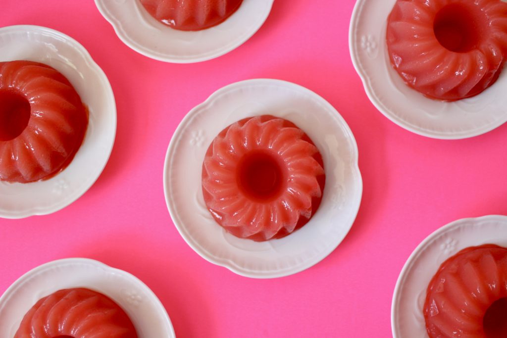 Pink watermelon pudding monoportions served on white porcelain dishes on a neon pink base