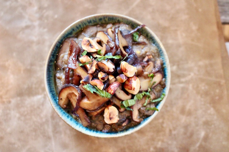 Lentil Miso soup with Shiitake mushrooms and hazelnuts served in a green bowl