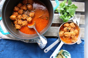 meatballs braised in a pot with broth, wine and bay leaves