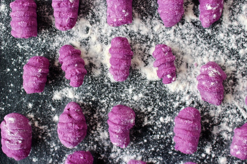 purple gnocchi on a floured black tray