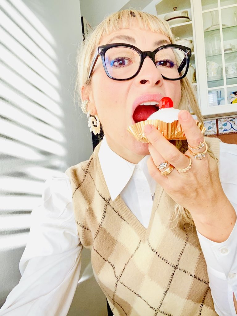 blond girl with black eyeglasses eating a pastry with a cherry on top